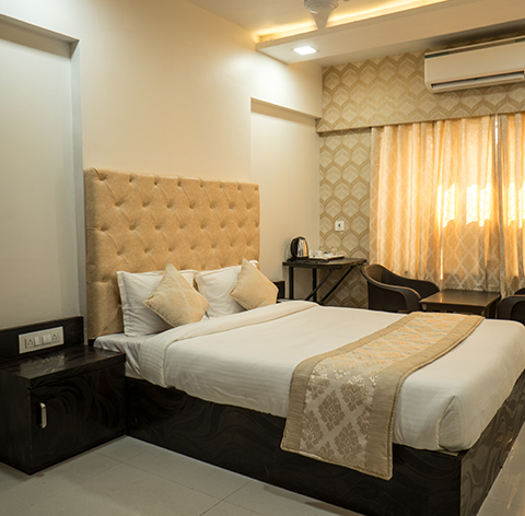 Deluxe room with a tufted headboard and made-up double bed